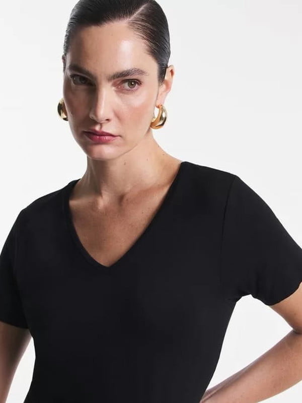 Blusas femininas para uniforme: modelo vestindo uma blusa básica em meia malha com decote V preta - detalhes.