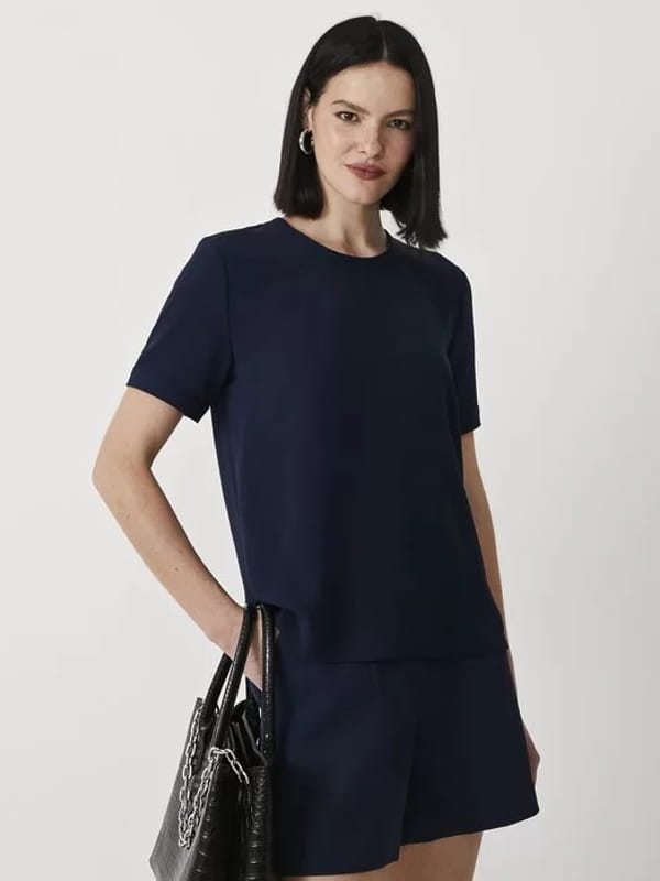 Blusas femininas para uniforme: modelo vestindo uma blusa com abertura nas costas e detalhes pespontados.