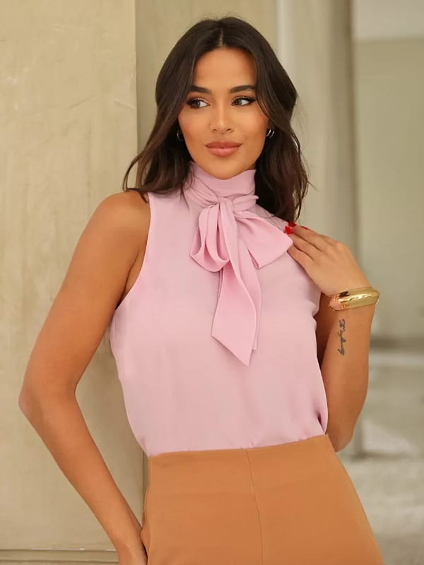 Blusa com laço na gola: modelo vestindo uma blusa de laço na gola na cor rosa.