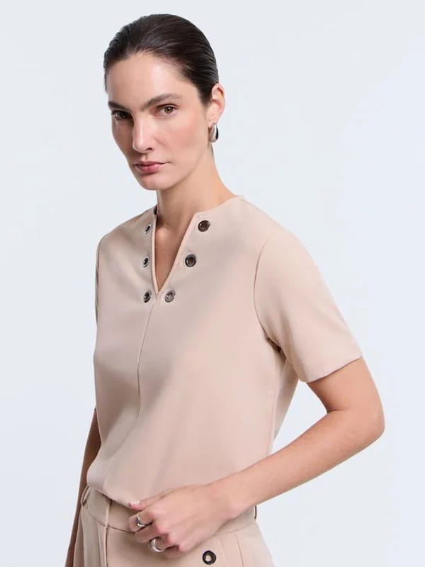 Blusa feminina de crepe: modelo vestindo uma blusa em crepe com decote V e detalhe de ilhoses bege.