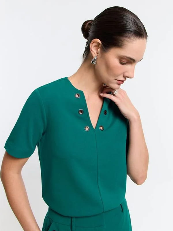 Blusa feminina de crepe: modelo vestindo uma blusa em crepe com decote V e detalhe de ilhoses verde.