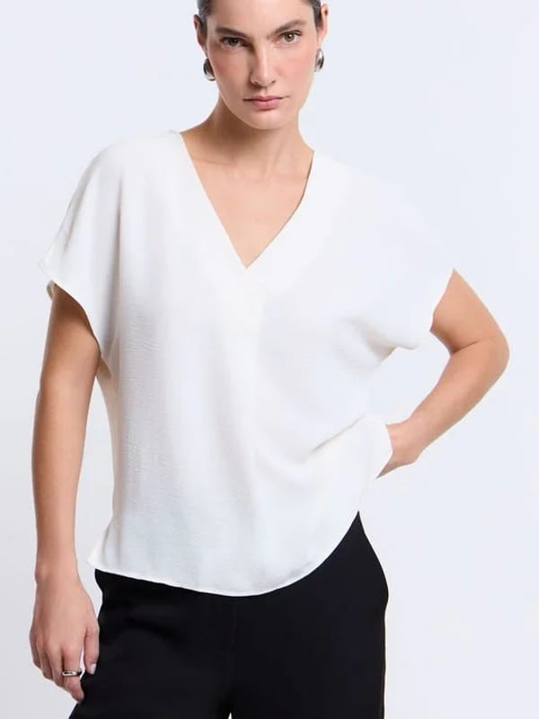 Blusa feminina de crepe: modelo vestindo uma blusa com decote V e fechamento frontal branca.