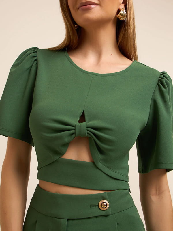 Blusa feminina de crepe: modelo vestindo uma blusa cropped em crepe com manga bufante e detalhe vazado verde - detalhes.