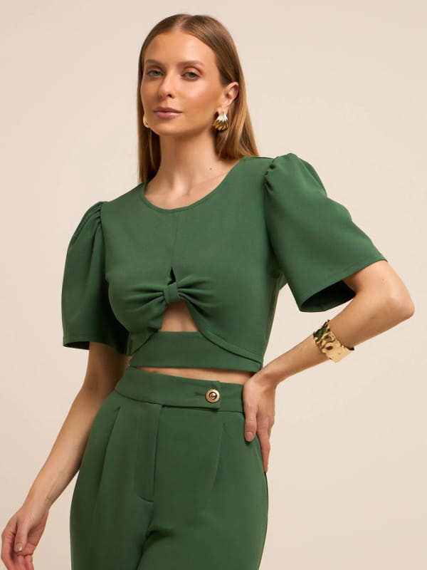 Blusa feminina de crepe: modelo vestindo uma blusa cropped em crepe com manga bufante e detalhe vazado verde.