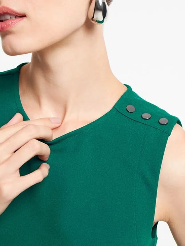 Blusa feminina de crepe: modelo vestindo uma blusa de crepe sem manga com botões nos ombros verde - detalhes.