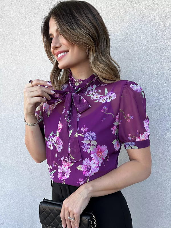 Blusa floral feminina: modelo vestindo uma blusa floral roxa com calça preta.