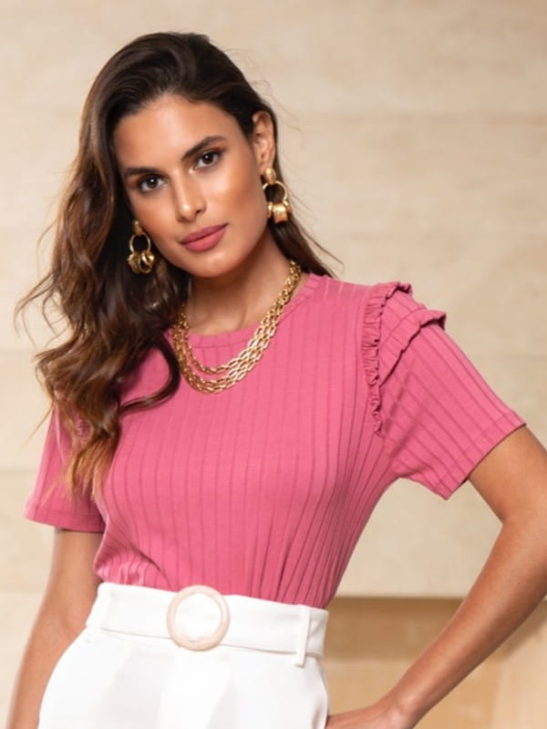 Looks com blusas caneladas: modelo vestindo uma blusa rosê com babados.