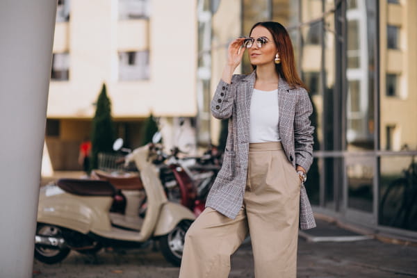 Calça pantalona feminina: mulher com a mão no bolso e segurando os óculos de sol.