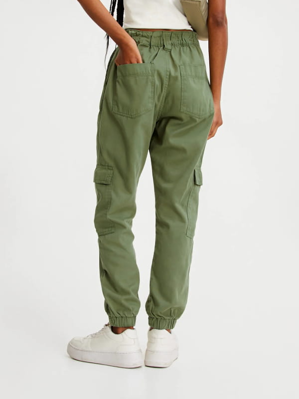 Looks com calça cargo feminina: modelo vestindo uma calça cargo feminina jogger cintura alta verde militar - costas.