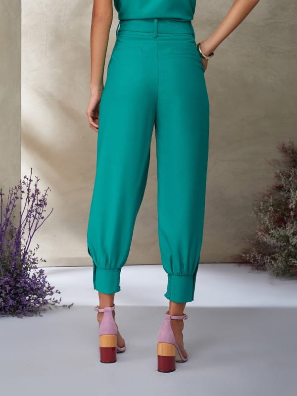 Looks com calça jogger feminina: modelo de costas vestindo calça de crepe e blusa verdes.