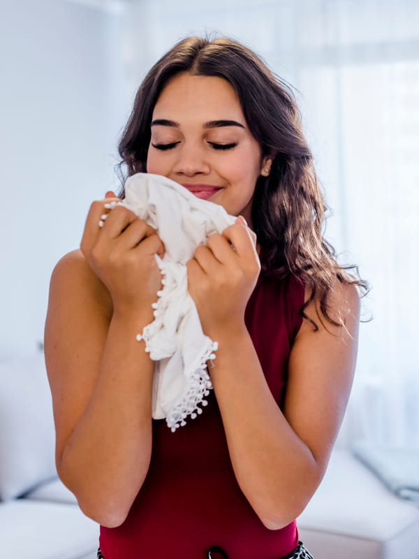 Como lavar blusa de tricot: moça cheirando sua blusa limpinha.