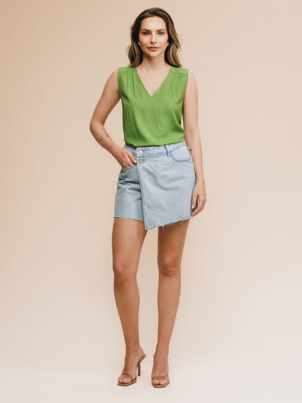 Cores que combinam com azul: modelo vestindo uma regata com decote V na cor verde com uma saia jeans - look.