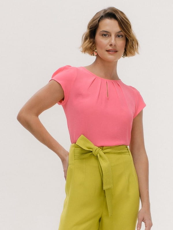 Cores que combinam com rosa: modelo vestindo uma blusa de crepe básica detalhe gota cor rosa e calça verde.