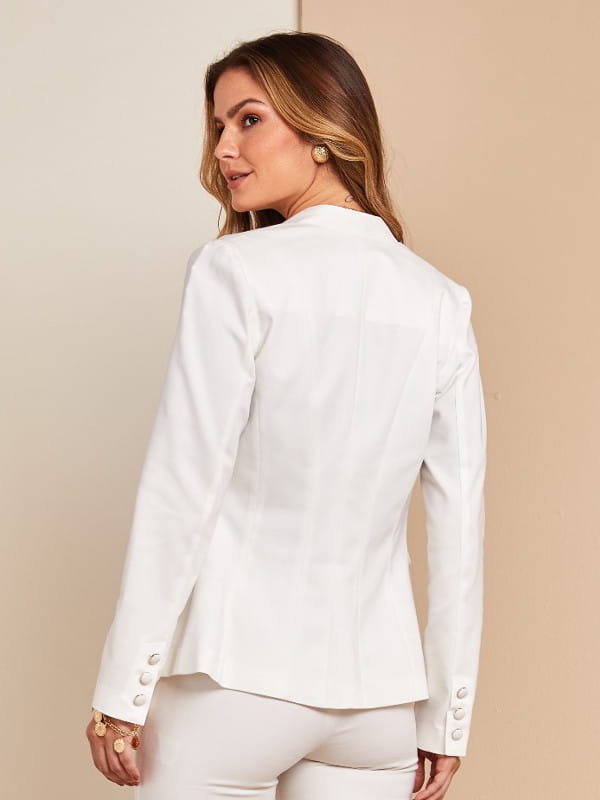 Looks com blazer branco feminino: mulher escolhendo modelos atrás de uma arara de roupas.