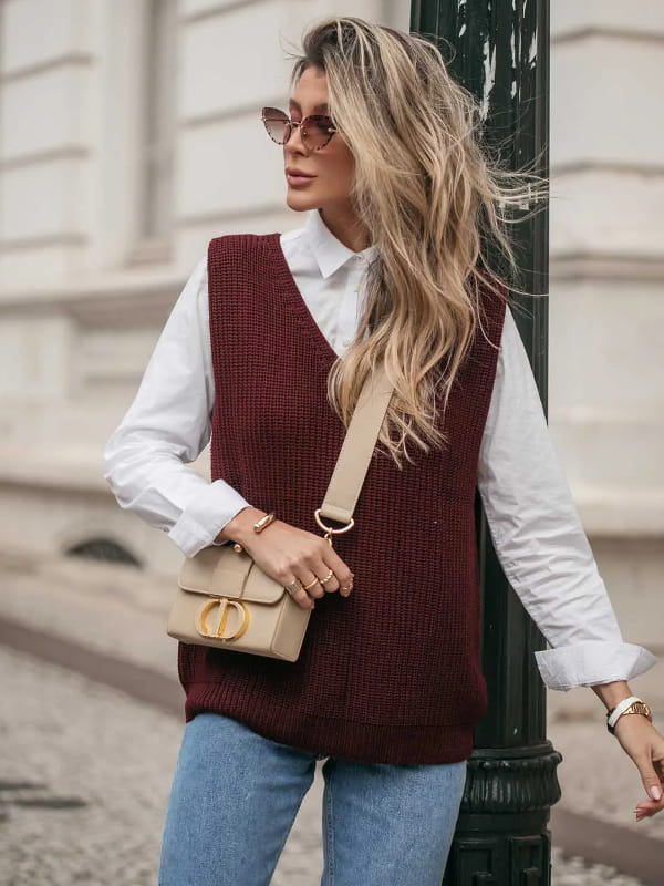 Looks para arrasar com a terceira peça: modelo vestindo um colete de tricot marsala e calça jeans.