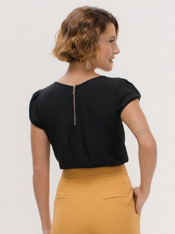 Que cor combina com preto: modelo vestindo uma blusa de crepe com detalhe gota no decote e calça caramelo - costas.