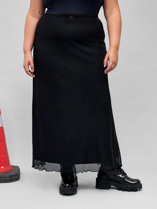 Coturno com saia midi: modelo usando uma saia midi em tule com frufru na barra curve plus size preta - detalhes.