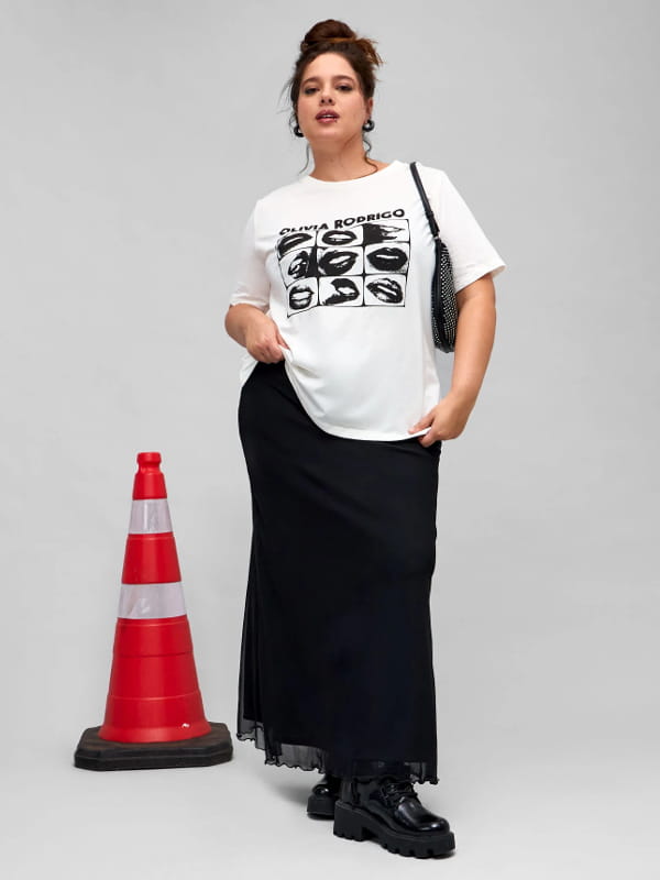 Coturno com saia midi: modelo usando uma saia midi em tule com frufru na barra curve plus size preta.