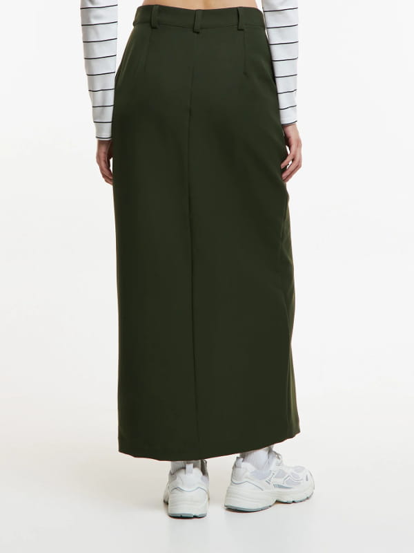 Look com saia midi e tênis: modelo vestindo uma saia midi em alfaiataria com fenda frontal verde - costas.