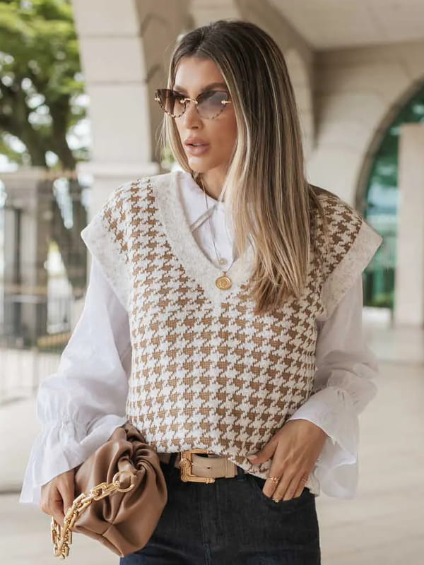 Casacos femininos para Outono Inverno 2023: modelo vestindo um colete de tricot gola V bege por cima de uma camisa branca.