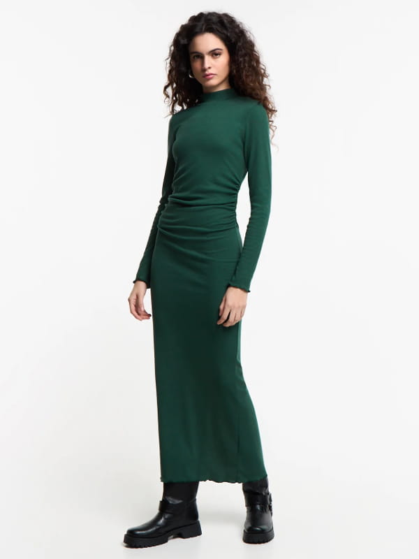 Vestido midi combina com coturno: modelo usando um vestido midi em ribana com golinha e fenda nas costas verde.