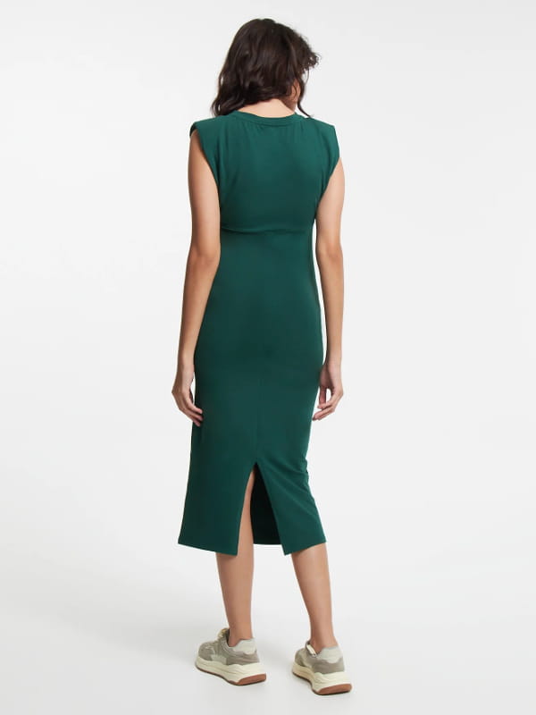 Como usar vestido midi com tênis: modelo usando um vestido midi em meia malha com ombreira e busto franzido verde escuro - costas.